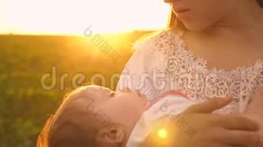 在夕阳的金色光芒中，婴儿在母亲的怀里睡着了。 慢动作